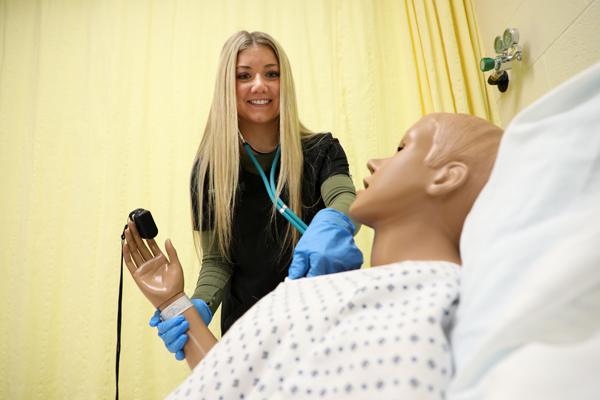 A female student taking a mannequin's pulse.